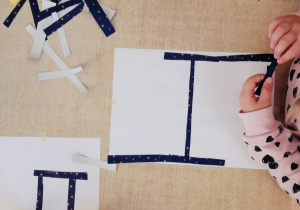 Dzieci wykonują prace plastyczne z wykorzystaniem papierowych linii.