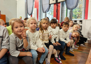 Dzieci siedzą na sali gimnastycznej