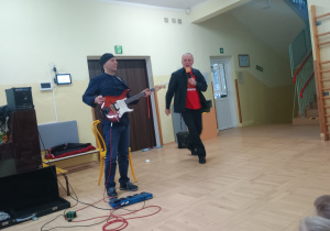 Pan pokazuje gitarę elektryczą