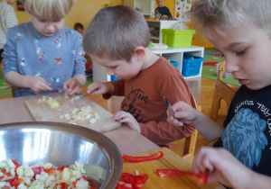 Dzieci kroją warzywa na sałatkę jarzynową