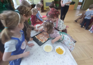 Dzieci wspólnie komponują pizzę