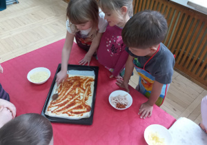 Dzieci układają pizzę na blachach