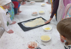 Dzieci wykładają ciasto na blachę