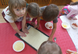 Dzieci układają ciasto na pizzę