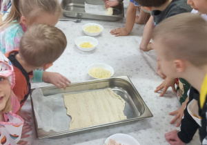 Dzieci rozciągają ciasto na pizzę