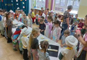 Nauczycielka objaśnia dzieciom sposób wykonania pizzy