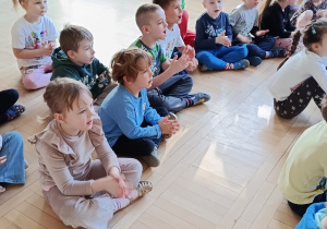 Dzieci siedzą na sali gimnastycznej