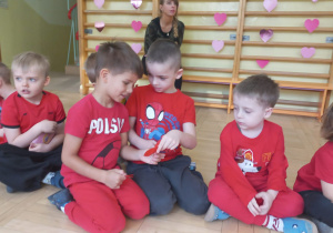 Dzieci oglądają rozdane przez nauczyciela walentynki