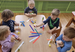 Dzieci tworzą papierowy łańcuch na choinkę.