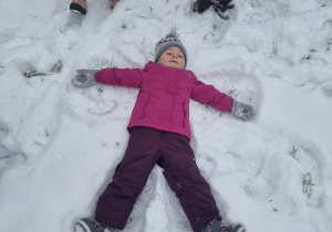 Poszukiwanie Mikołaja. Dziewczynka robiąca aniołka na śniegu.