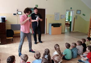 Dzieci siedzą na sali gimnastycznej podczas koncertu