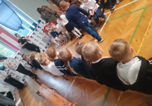 Dzieci siedzą na ławce na ślubowaniu klas pierwszych