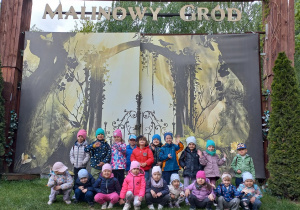 Dzieci z grupy III pozują do zdjęcia przy bramie z napisem Malinowy Gród.